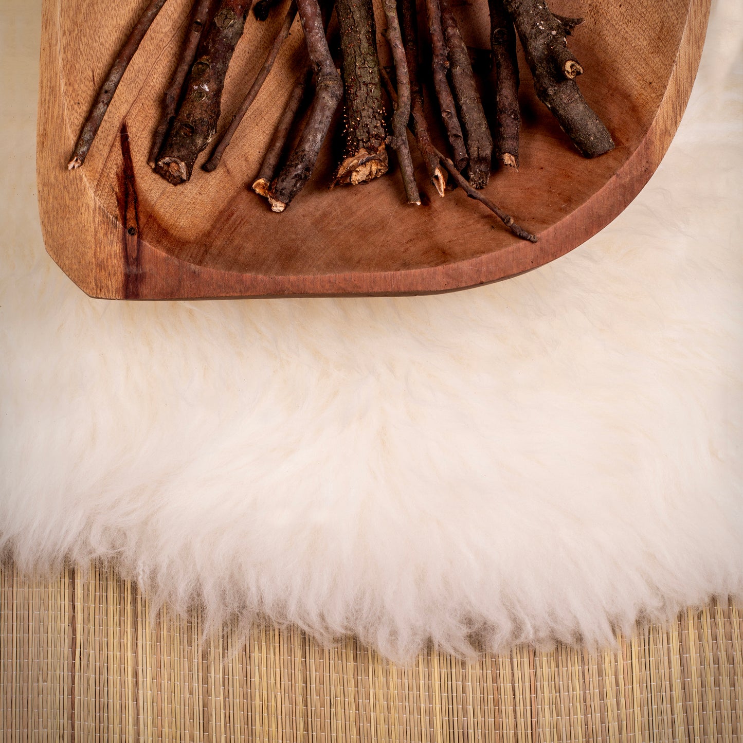 Close-up of natural ivory sheepskin rug with soft plush wool texture and wooden tray on top