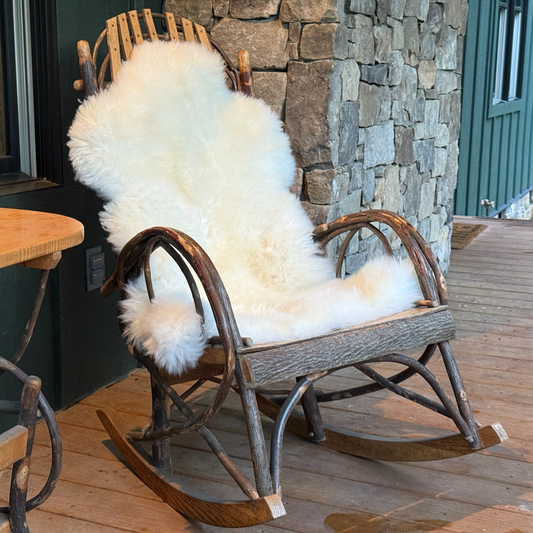 Natural sheepskin rug draped over a wooden rocking chair for cozy home decor
