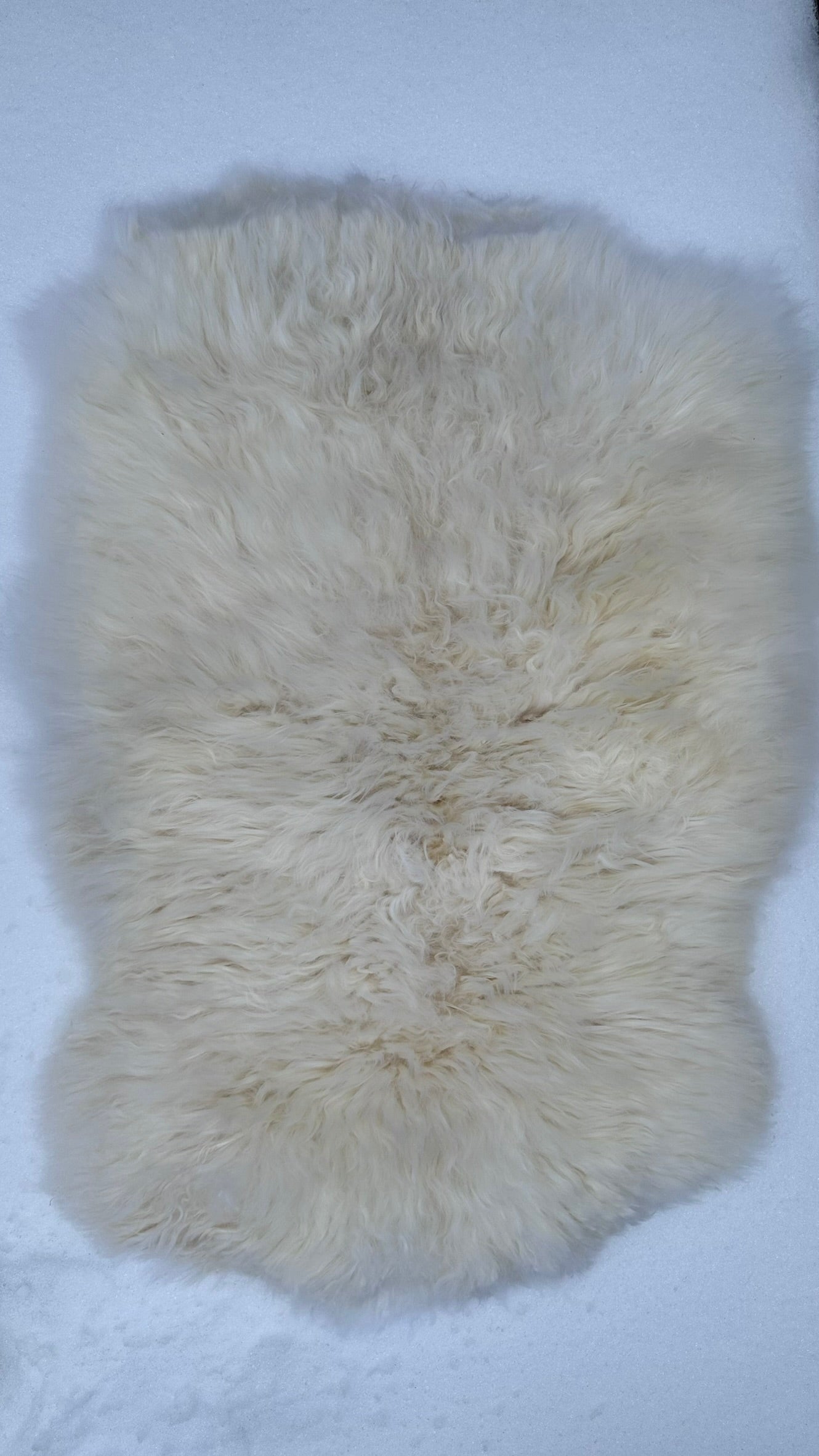 Natural sheepskin rug shown flat to display its organic shape and ivory tone
