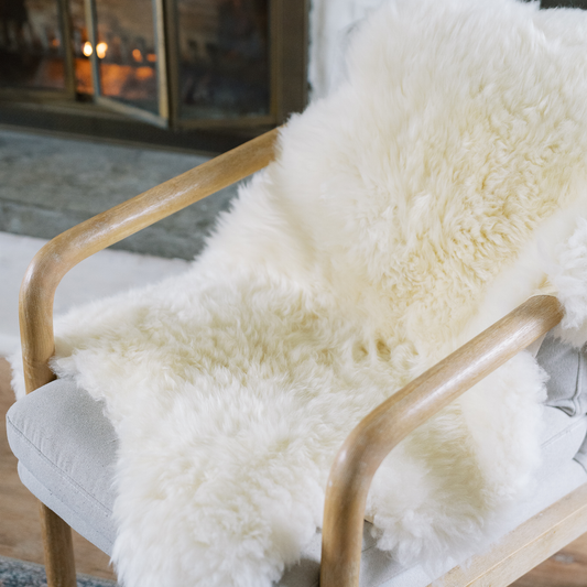 Natural sheepskin rug styled over a modern chair to add warmth and texture
