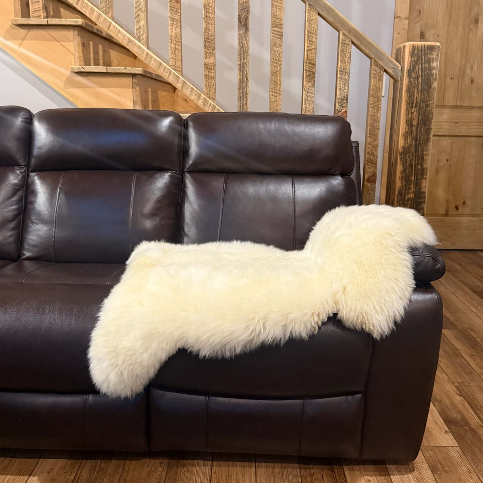 Natural sheepskin rug draped over a leather sofa for cozy living room decor
